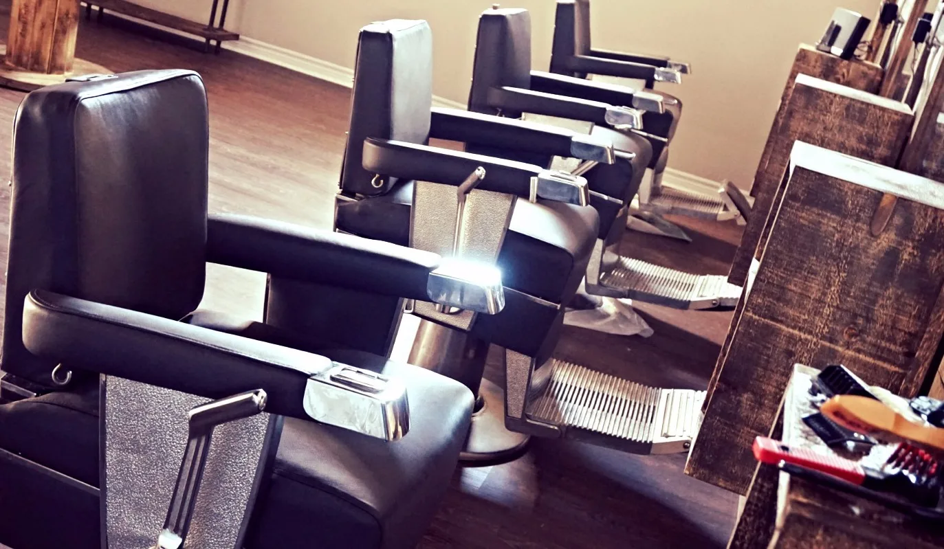 A row of classic black-leather and chrome barber chairs inside a New Style shop