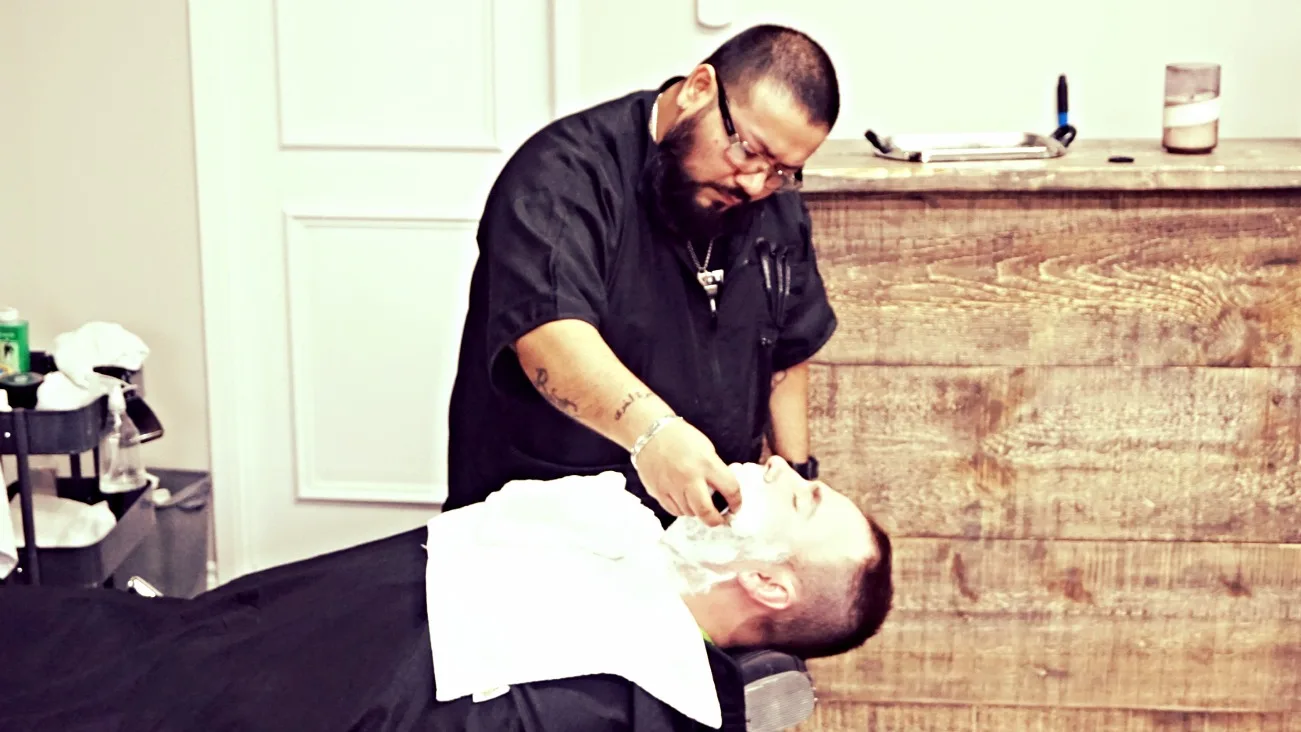 A New Style barber giving a client a hot-towel straight-razor shave