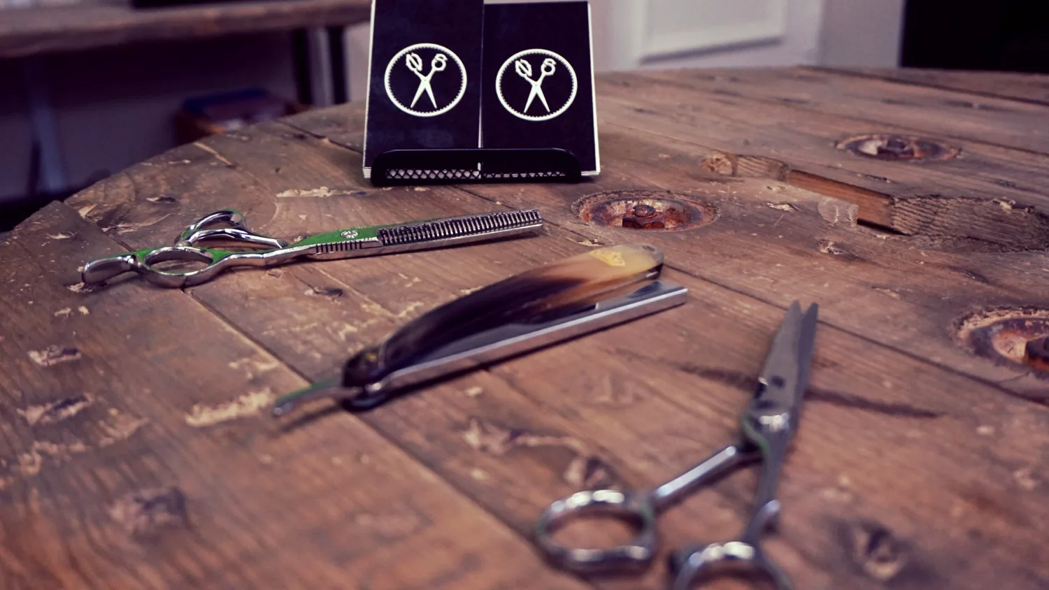 Barber shears, a straight razor and scissors on a reclaimed-wood table